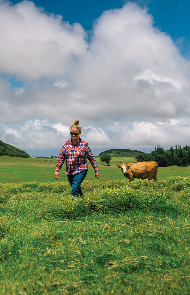 ranch person in the field with a brown cow. 