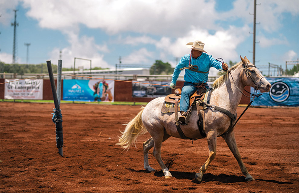 professional cowboy riding white horse dressed in turquoise colors.